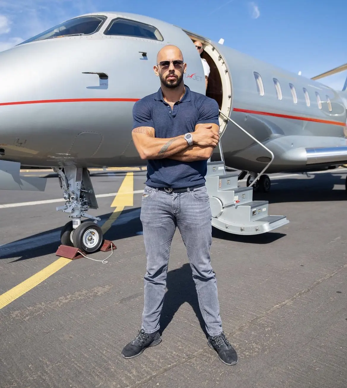 Andrew Tate standing in front of a private jet